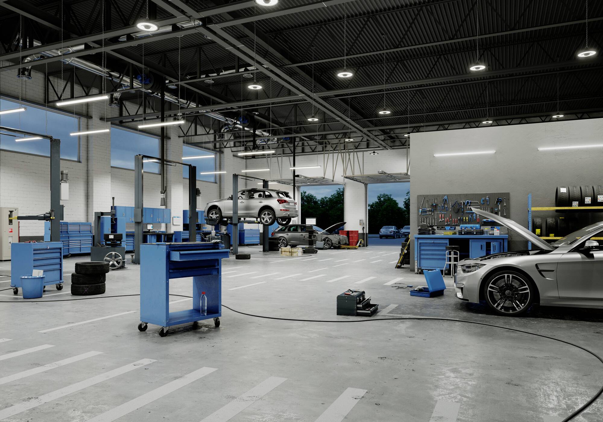 In einer Autowerkstatt stehen mehrere Autos auf Hebebühnen. Ein Auto ist hochgehoben, während ein anderes mit geöffneter Motorhaube steht.