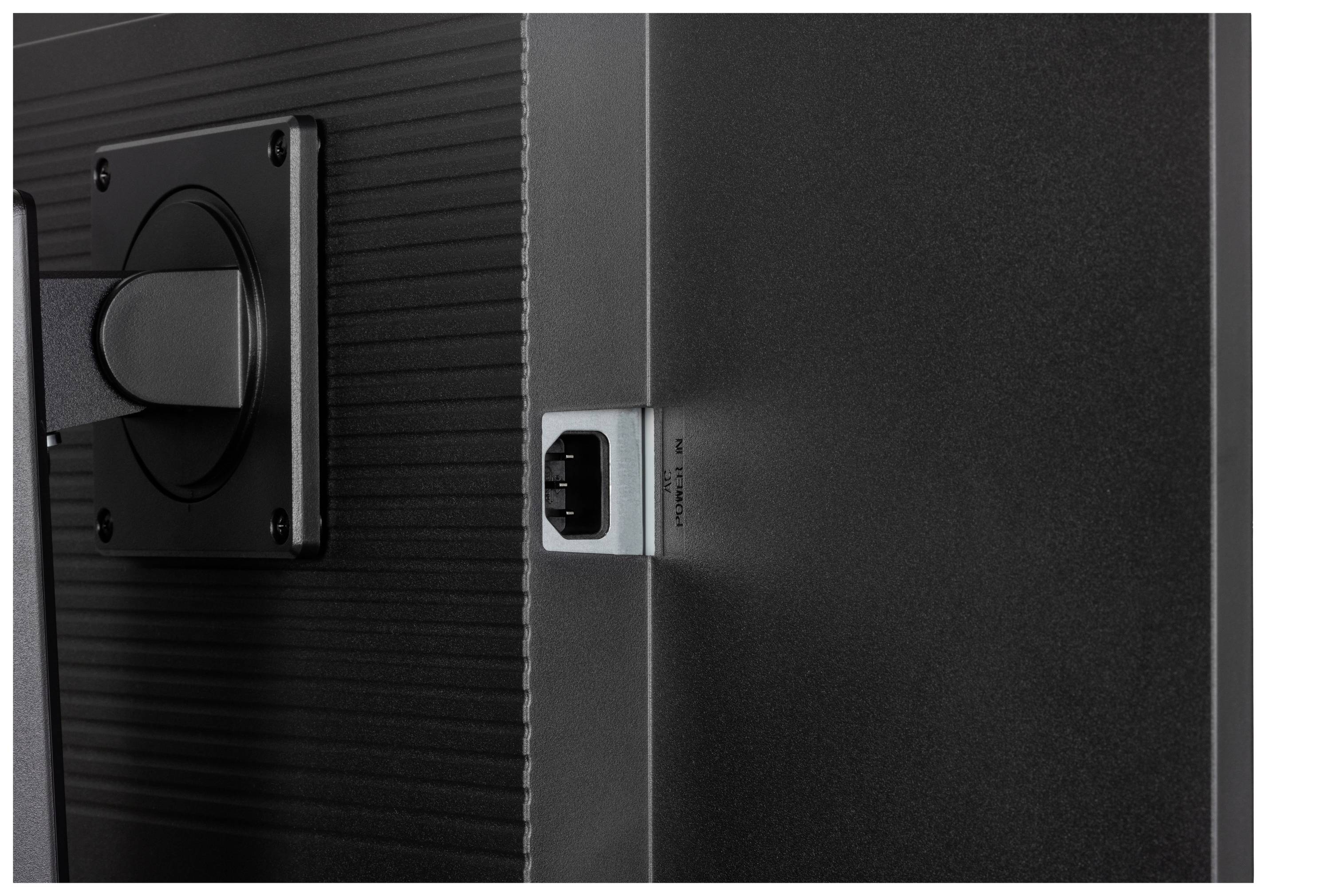 Rückseite eines Monitors mit einem Stromanschluss. Erkennbar ist ein Standfuß links im Bild.