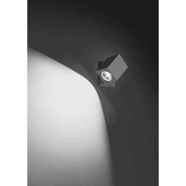 Eine moderne, quadratische Deckenleuchte leuchtet hell in einem ansonsten dunklen Raum und beleuchtet eine weiße Wandfläche.