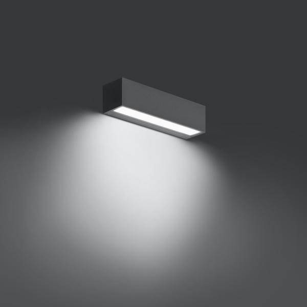 Rechteckige Wandleuchte aus Metall, beleuchtet eine graue Wand nach oben und unten, erzeugt weiches, diffuses Licht.