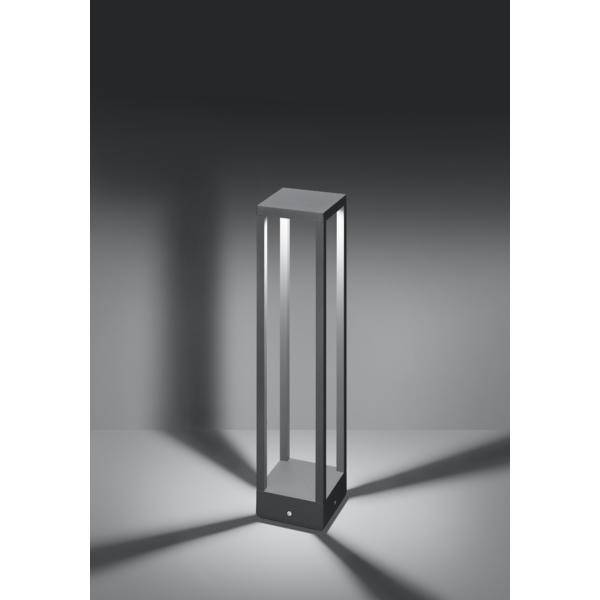 Schwarze, moderne Stehlampe in rechteckiger Form, leuchtet in mehreren Richtungen, wirft geometrische Schatten auf den Boden.