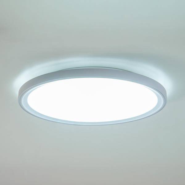 Runde Deckenleuchte, eingeschaltet, mit hellem, weißem Licht an einer weißen Decke. Minimalistisches Design in modernem Raum.