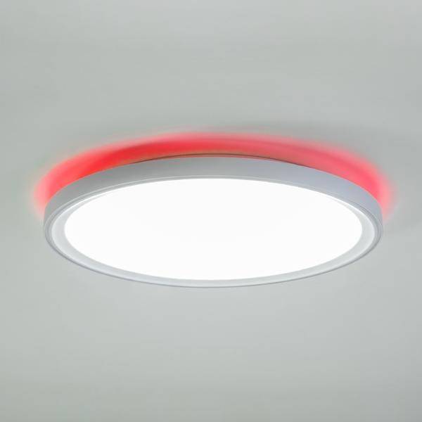 Eine runde, weiße Deckenlampe mit rotem Lichtschein am Rand, beleuchtet die Decke in einem modernen Raumdesign.
