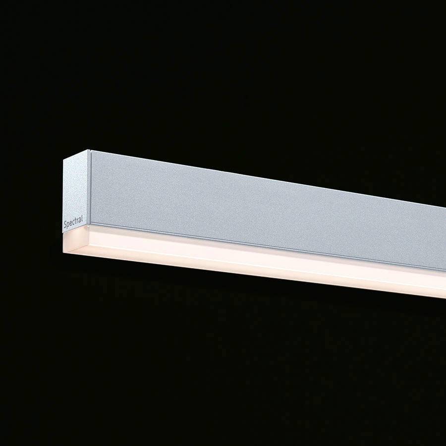 Rechteckige LED-Leuchte mit grauem Gehäuse und weißer Leuchtfläche, schwebt vor schwarzem Hintergrund.