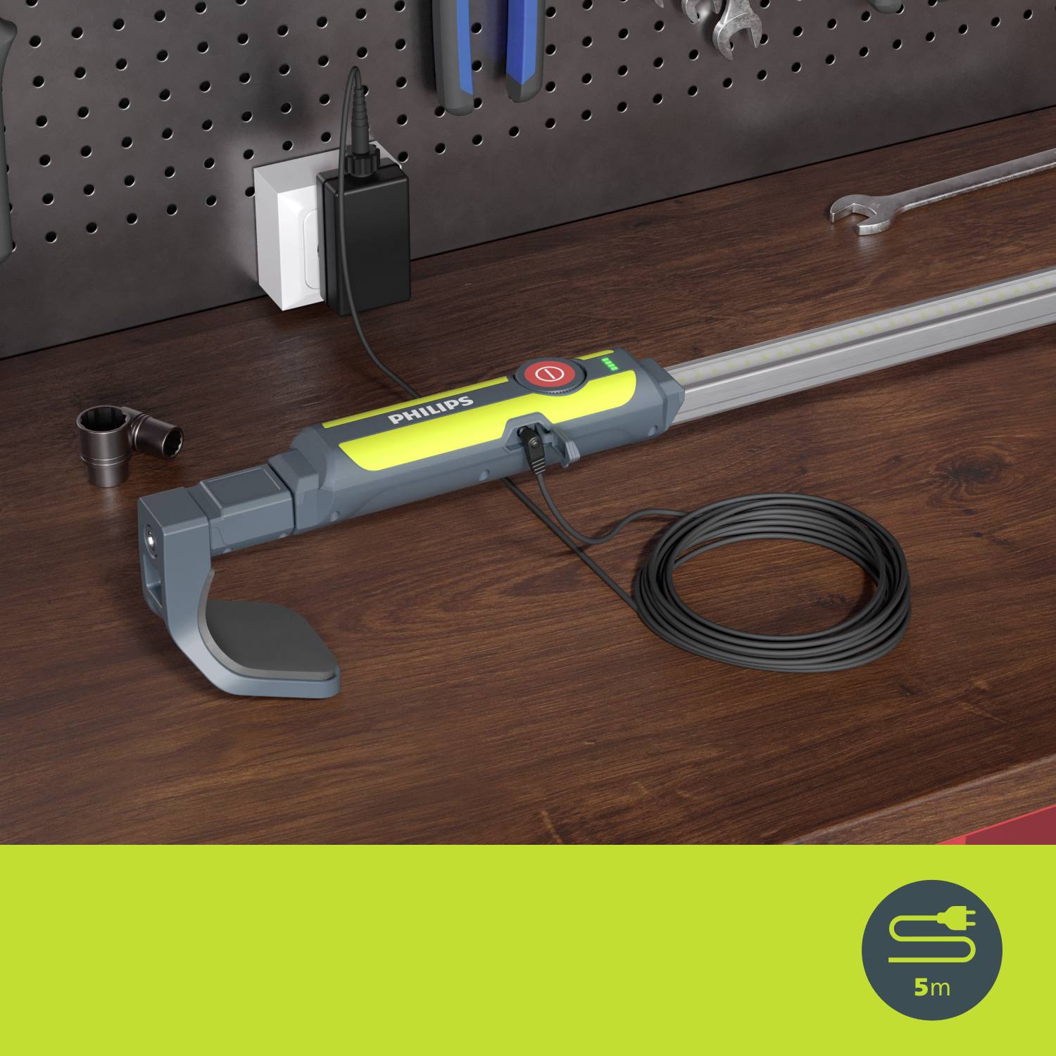 Ein langer, grauer Arbeitslichtstab liegt auf einer Werkbank neben Steckdosen und Werkzeugen. Kabel ist aufgerollt. Markiert als Philips.
