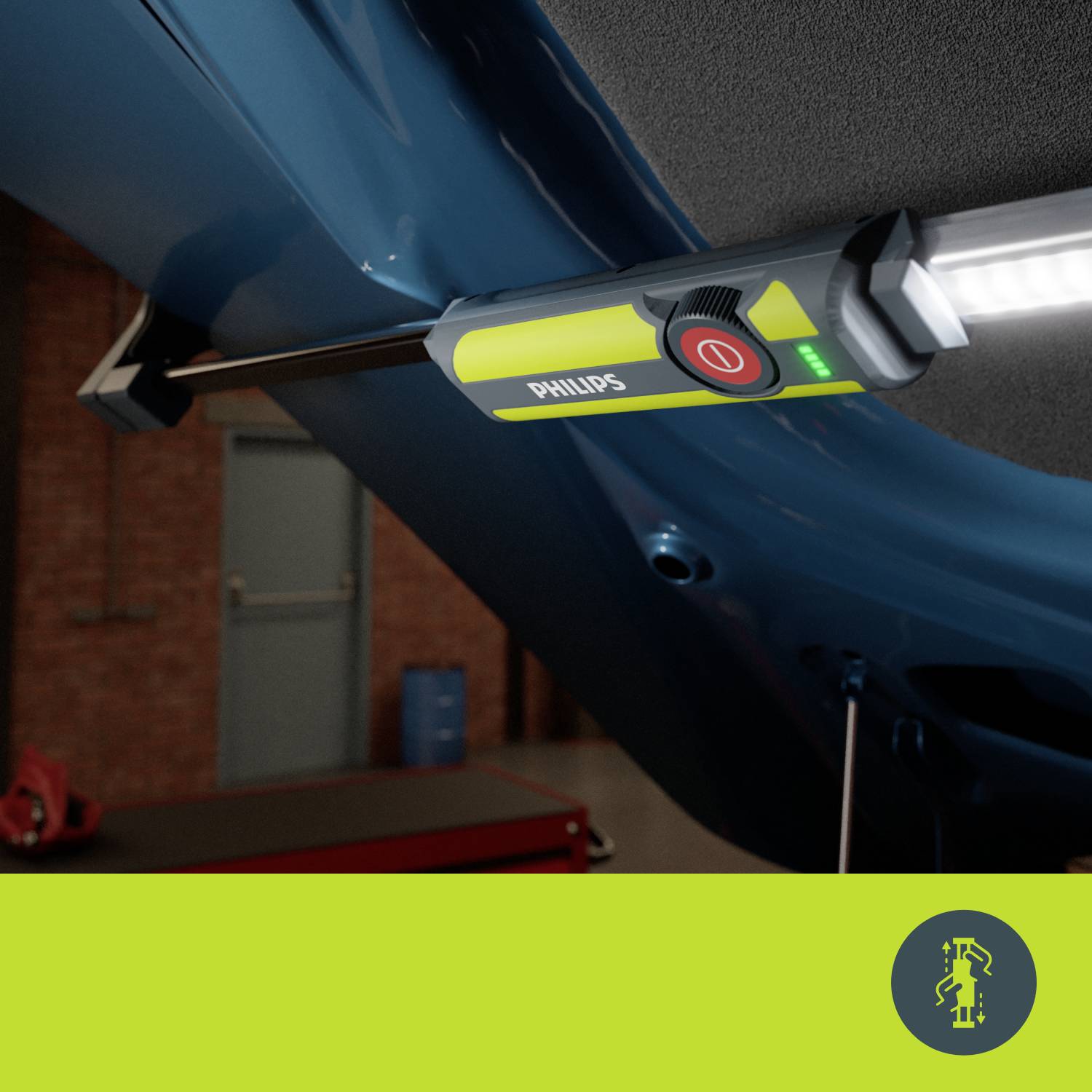 Eine dunkle Garage mit einer leuchtenden Arbeitslampe zeigt einen blau-grünen Autospoiler nahe einer Wand.