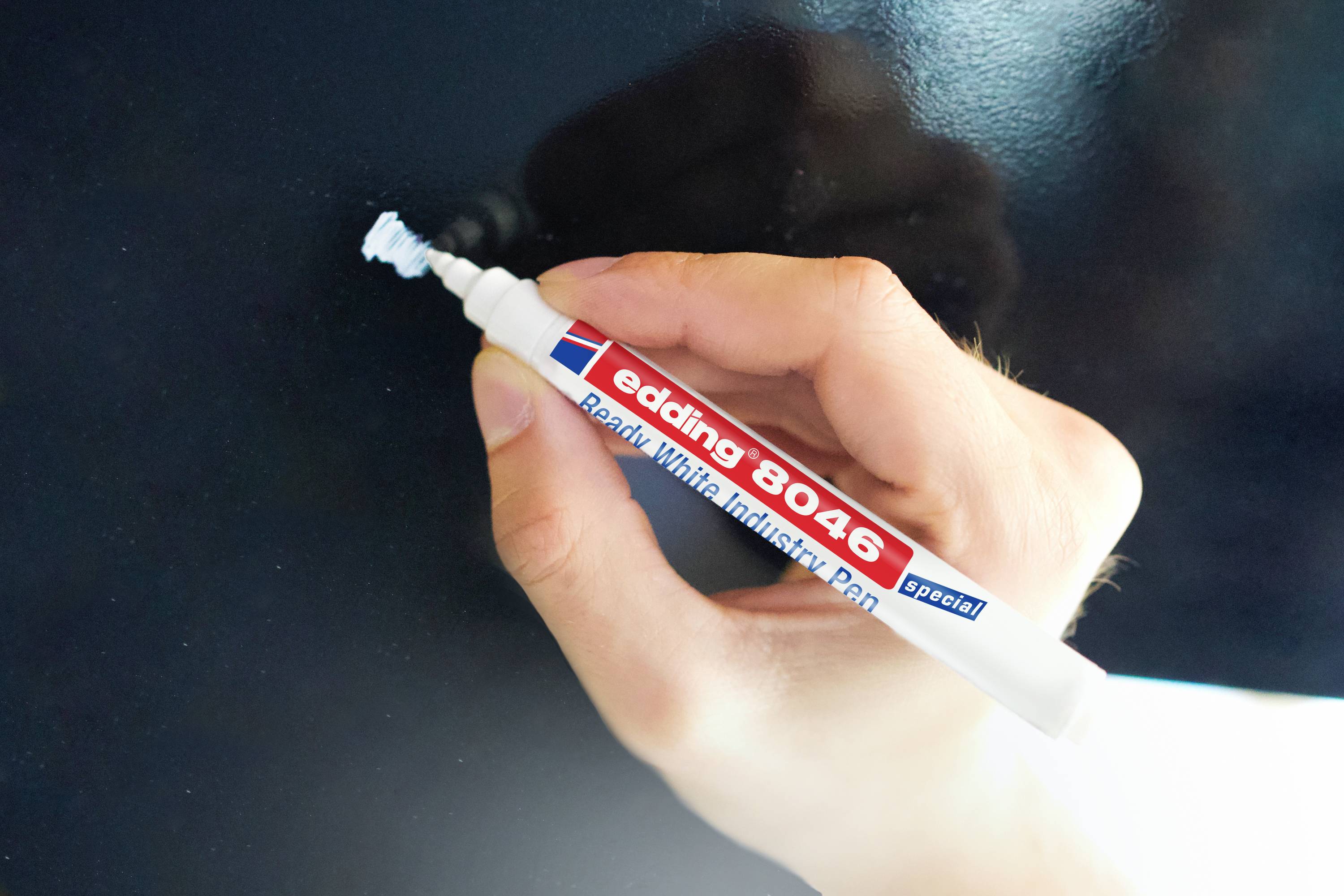 Eine Hand schreibt mit einem weißen Marker auf eine Tafel.