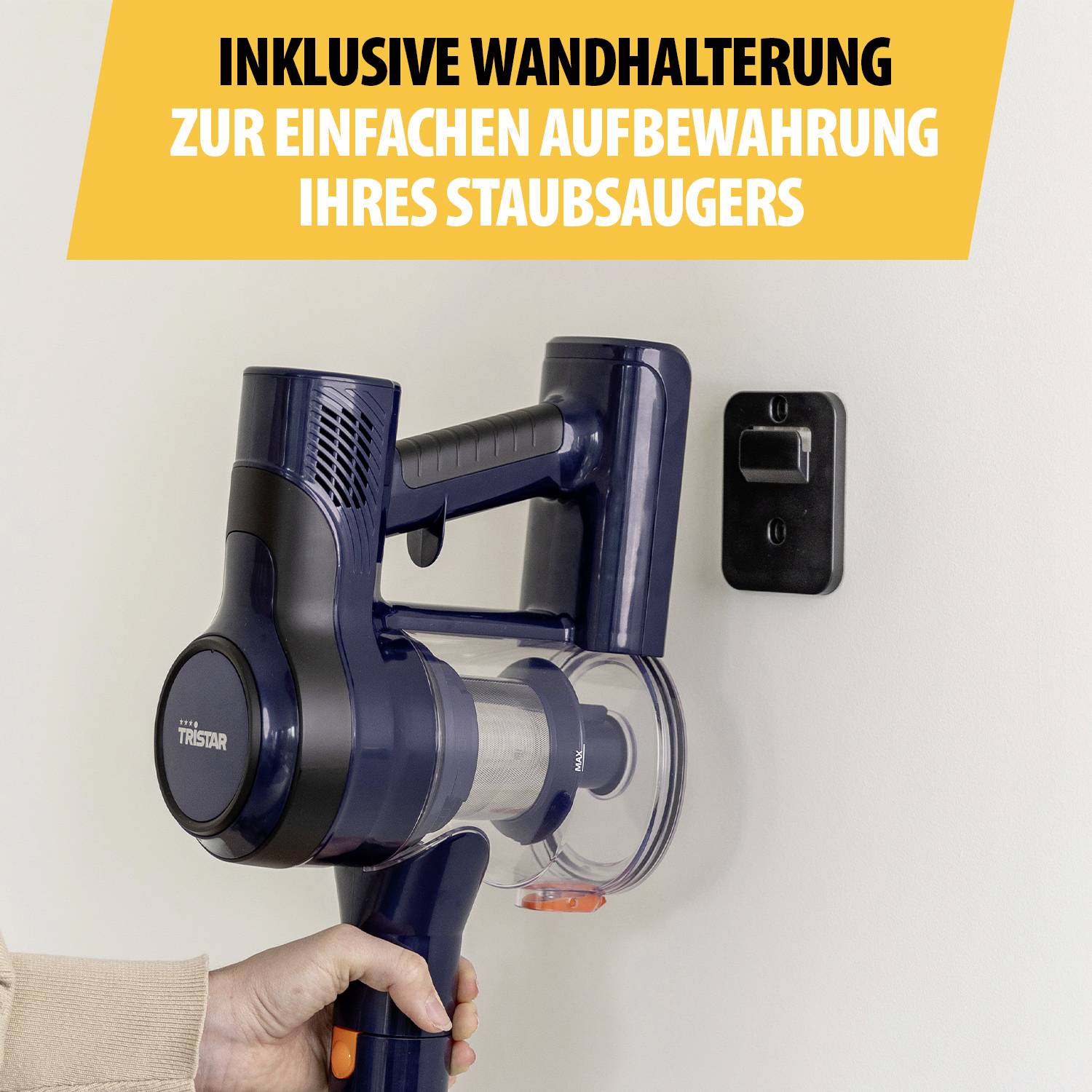 'Inklusive Wandhalterung zur einfachen Aufbewahrung Ihres Staubsaugers.' Eine Hand platziert einen Staubsauger an der Wandhalterung.
