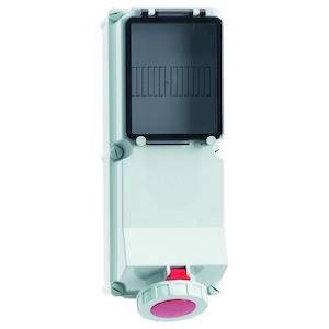 Ein graues elektrisches Gehäuse mit einem schwarzen Deckel, darunter ein roter Knopf. Es scheint ein Schalter oder ein Kontrollgerät zu sein.