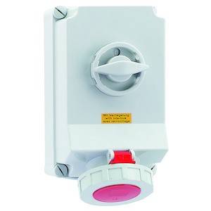 Ein weißer elektrischer Drehschalter mit roter Anzeige, montiert an einer Wand. Er hat eine gelbe Beschriftung für die Bedienungsanweisung.
