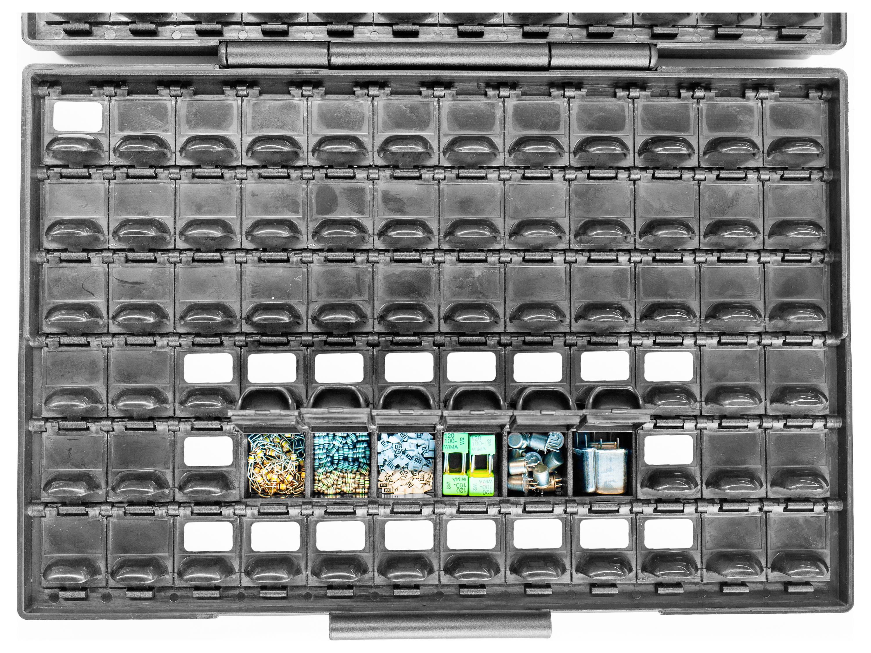 Leere graue Aufbewahrungsbox mit transparenten Fächern. In der Mitte sind fünf bunte Gegenstände platziert.