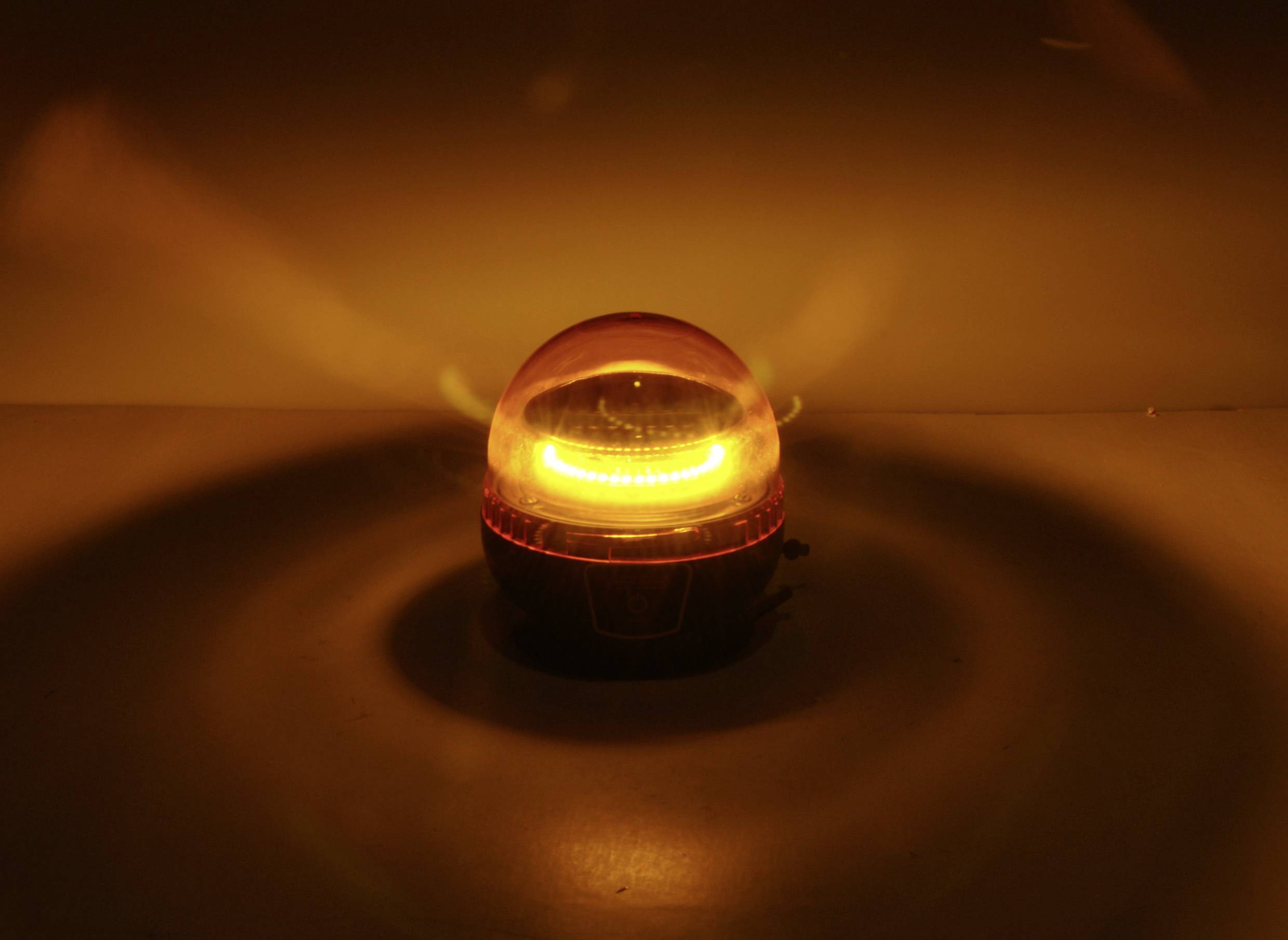 Leuchtendes oranges Nachtlicht auf einem Tisch in einem dunklen Raum, strahlt warmes, beruhigendes Licht aus.