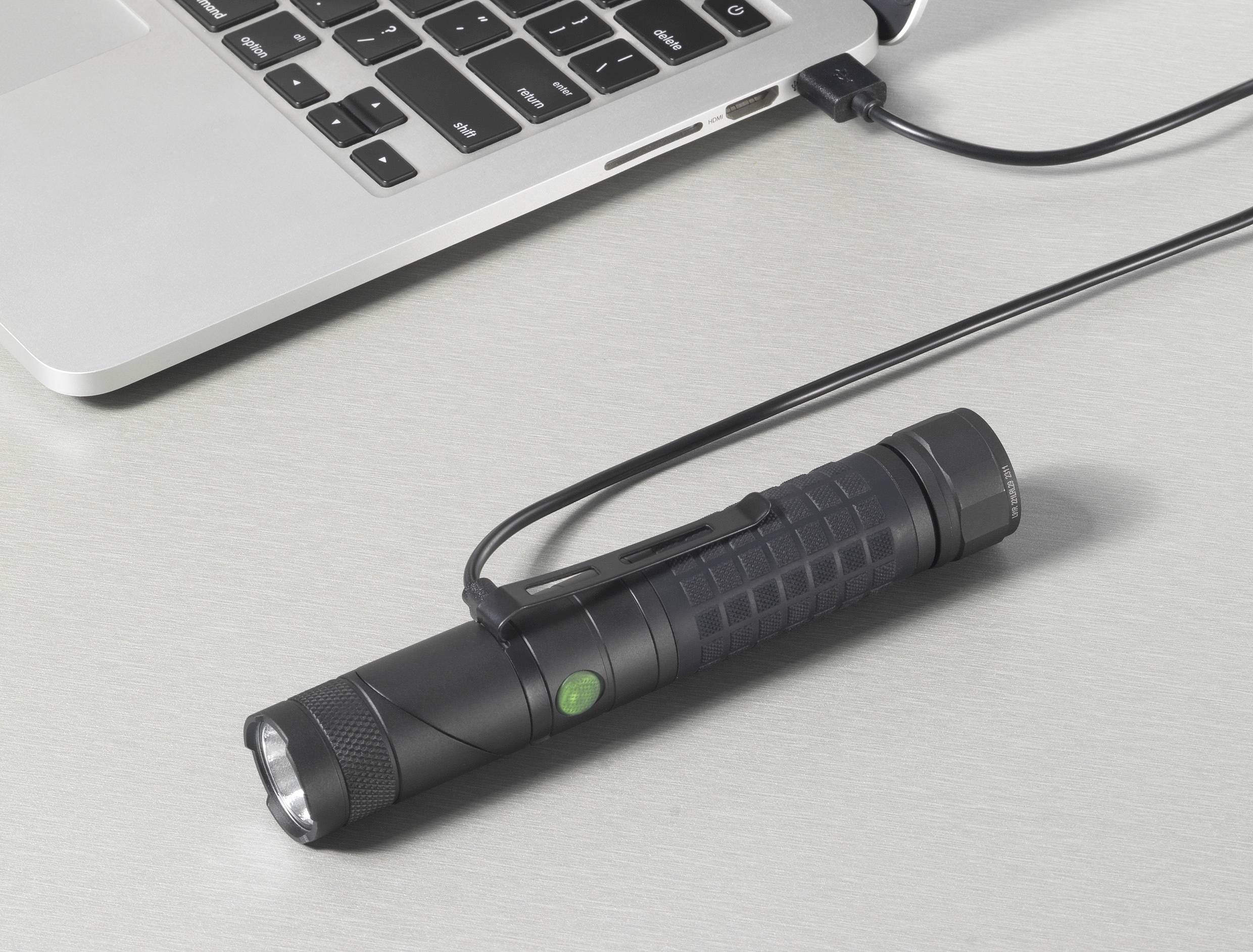 Eine Taschenlampe mit einem USB-Kabel ist auf einem Tisch neben einem Laptop angeschlossen.