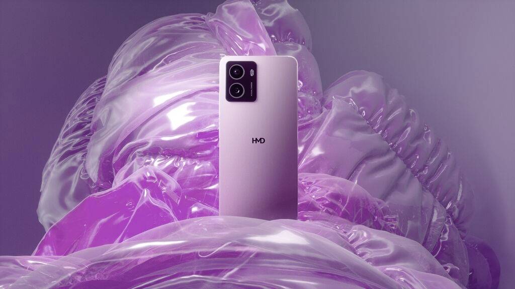 Ein rosa Smartphone mit drei Kameralinsen, umgeben von lila, durchscheinendem Stoff, was eine elegante und moderne Ästhetik vermittelt.