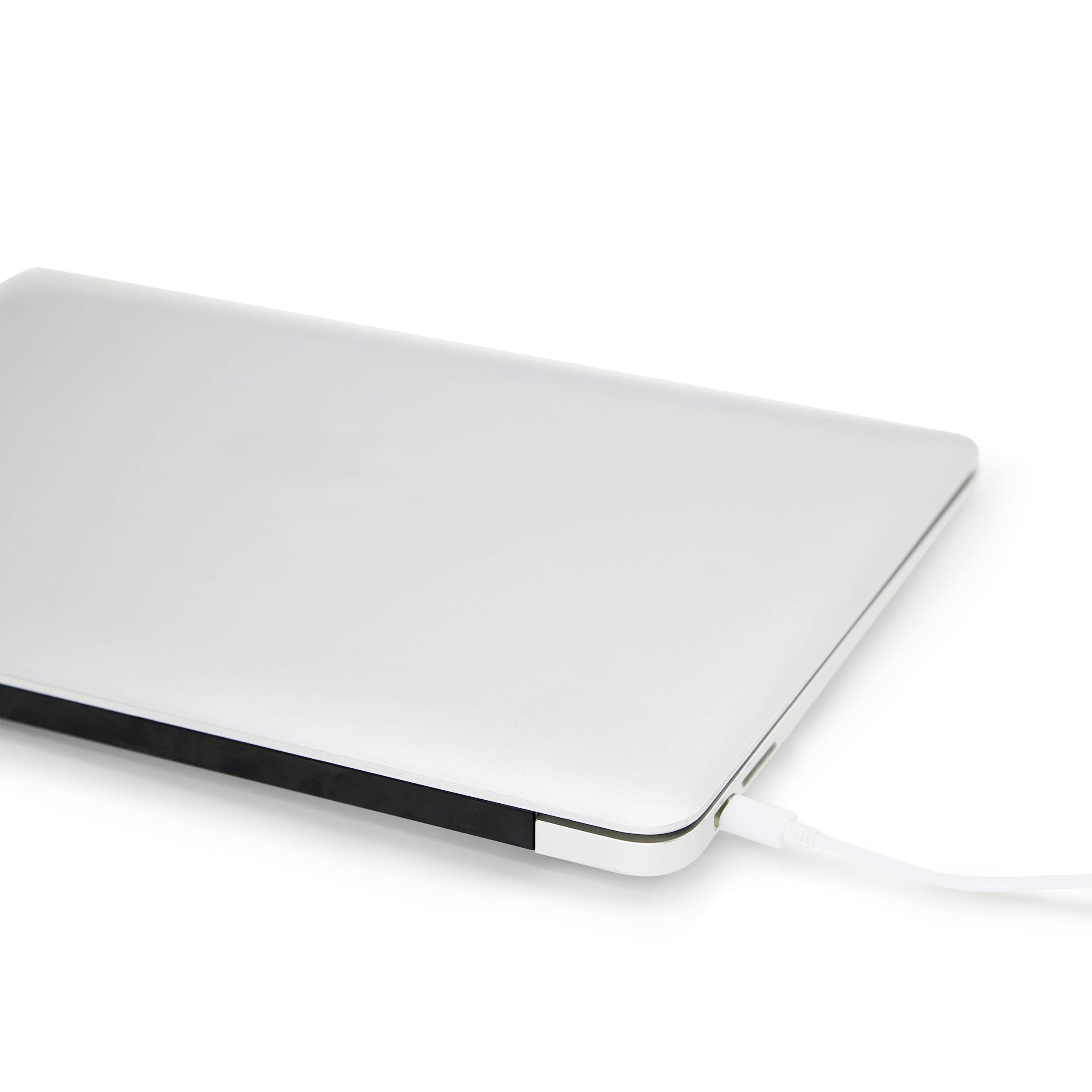 Der Laptop liegt geschlossen auf einem weißen Tisch und wird über ein Ladekabel aufgeladen.