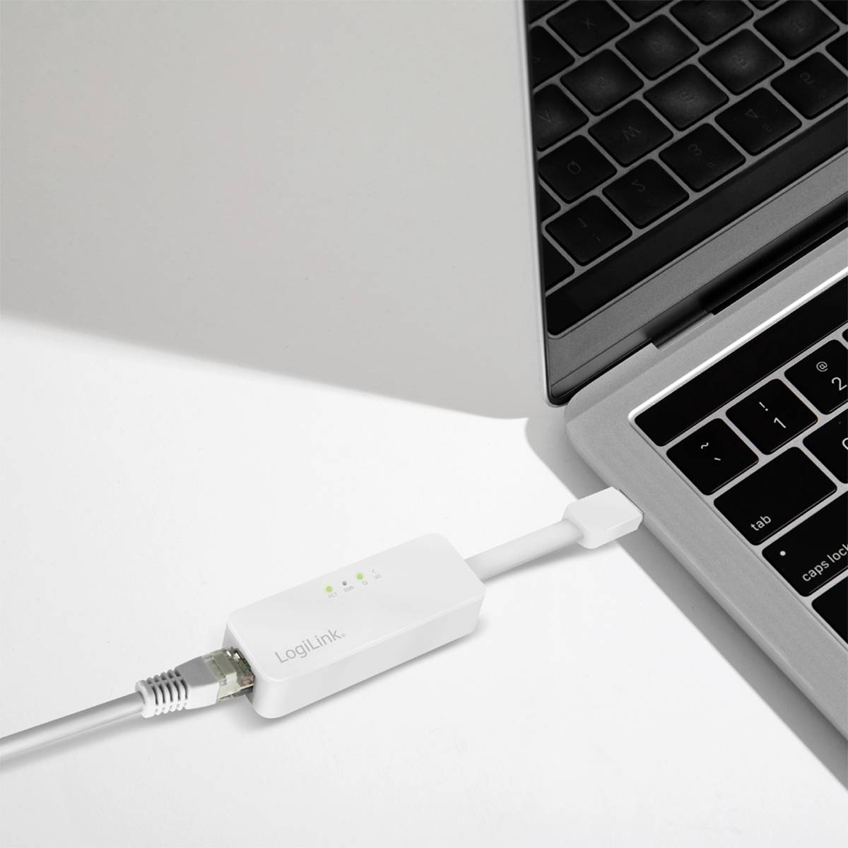 Ein Laptop ist per USB-Kabel mit einem Ethernet-Adapter verbunden, der 'LogiLink' zeigt und drei grüne LED-Anzeigen hat.