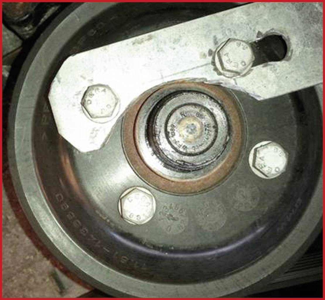 Ein Silberzahnrad mit erkennbaren Schrauben und Rostspuren, montiert an einem Metallarm.