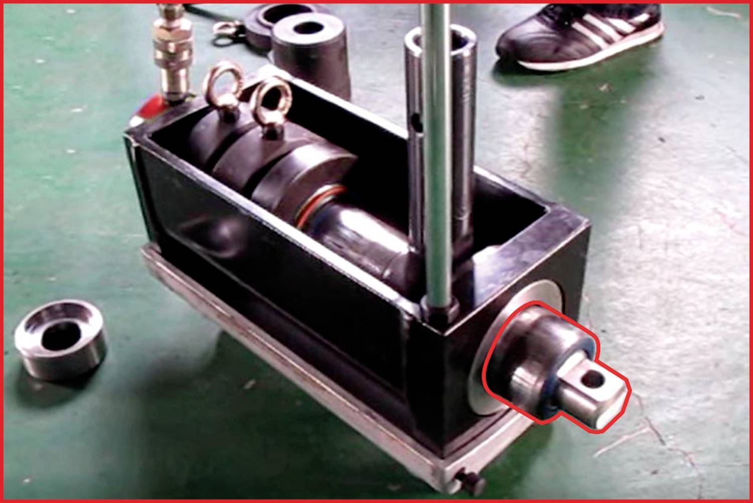 Ein Hydraulikzylinder befindet sich auf einem grünen Boden, teilweise geöffnet, mit sichtbaren internen Komponenten.