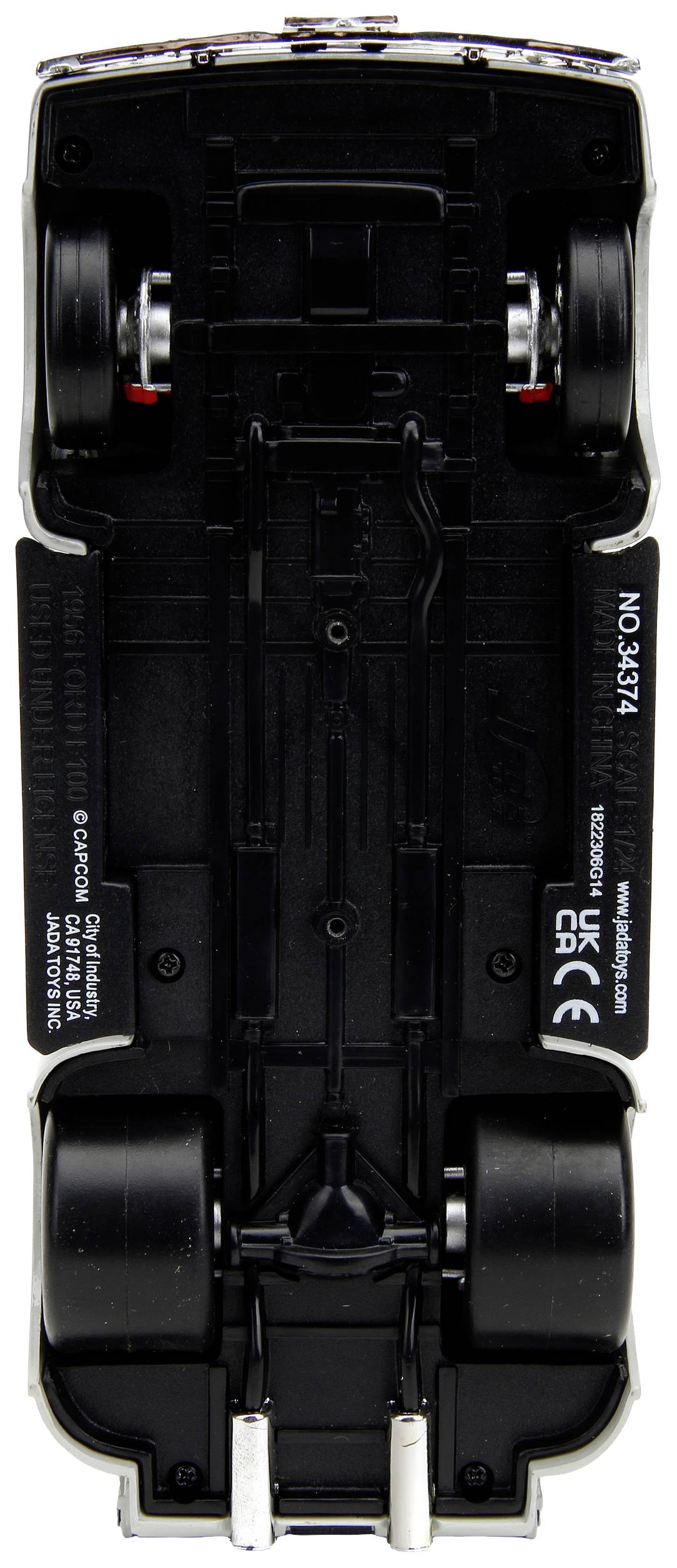 Das Bild zeigt die Unterseite eines Spielzeugautos mit sichtbaren Achsen, Rädern und Details des Fahrgestells.