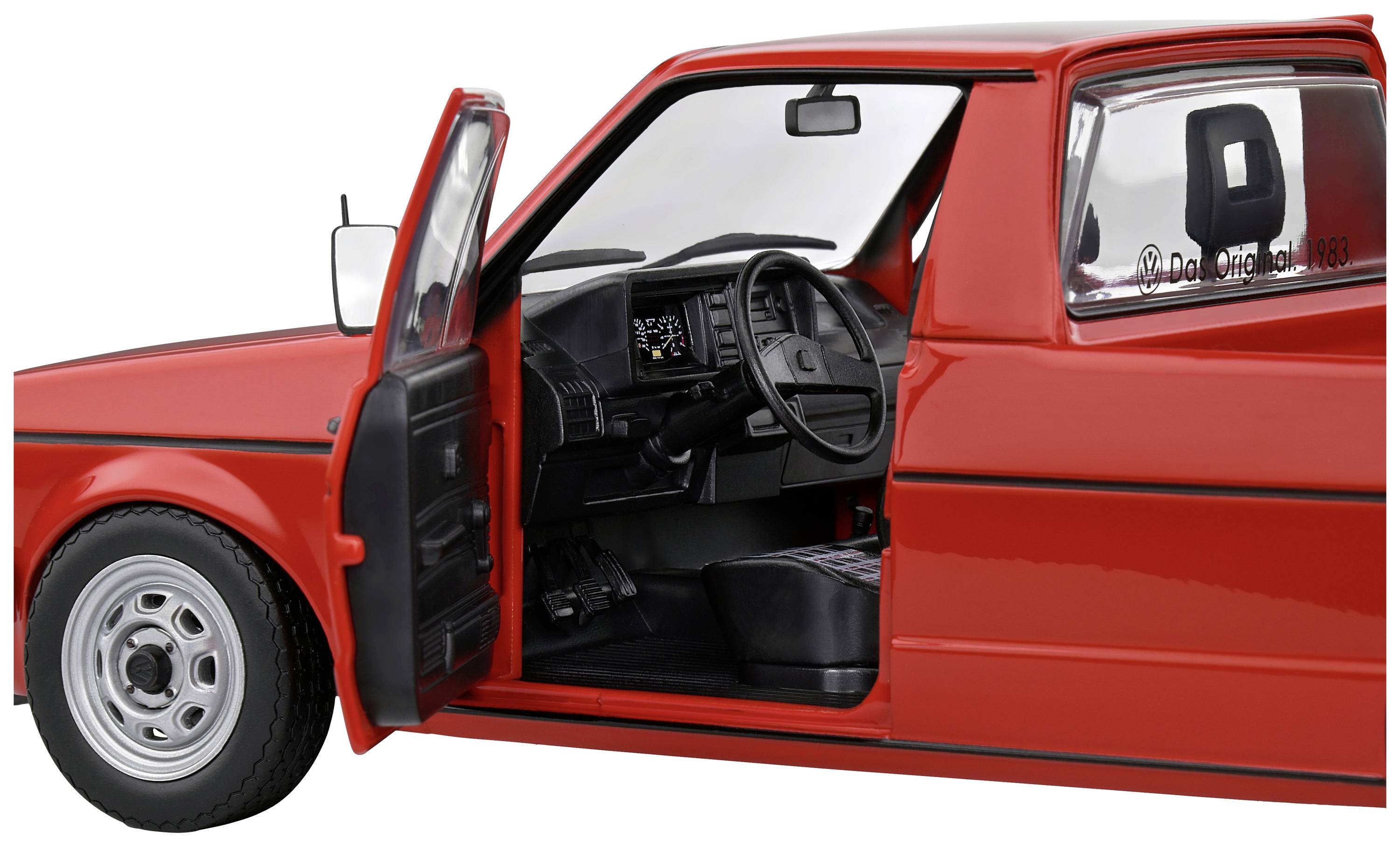 Ein rotes Auto mit offener Fahrertür zeigt das Lenkrad und das Armaturenbrett. Der Wagen ist kompakt und klassisch gestaltet.