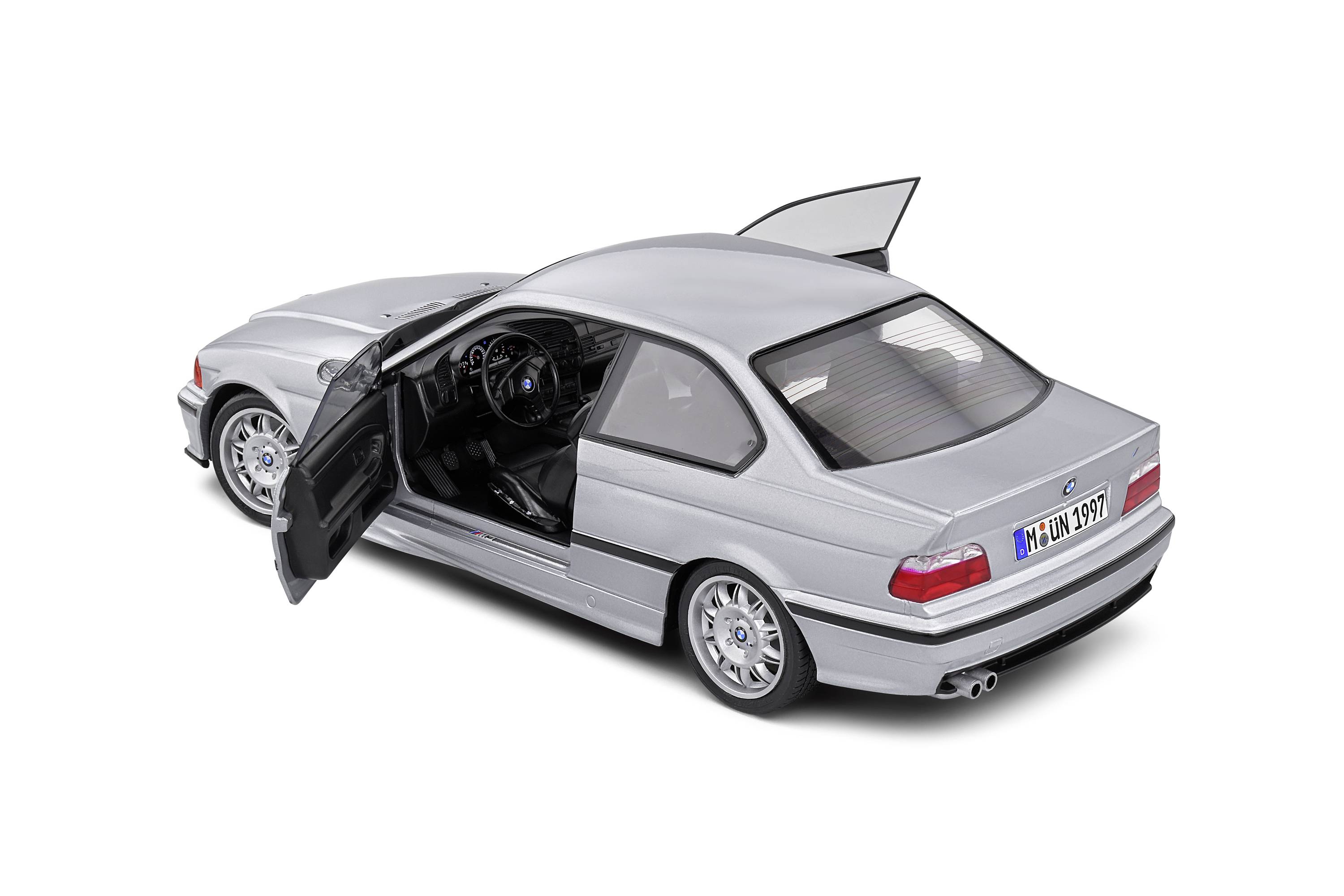 Ein silbernes Modellauto mit geöffneten Türen und offenem Kofferraum, zeigt Innen- und Heckdetails. Sportliches Design, sichtbares Nummernschild.