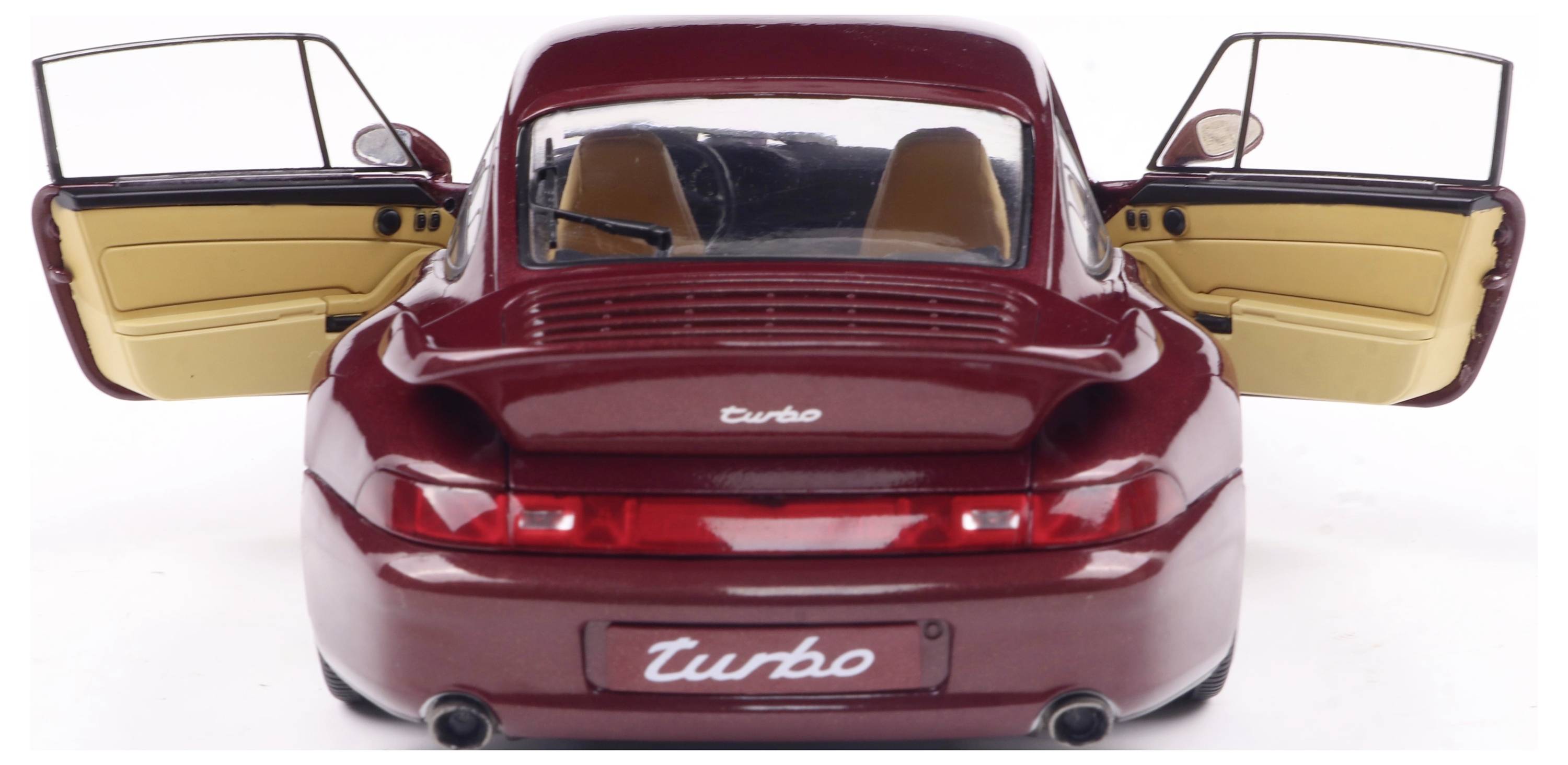 Roter Sportwagen mit offenstehenden Türen, Heckansicht. Schriftzug 'Turbo' auf Kofferraum. Innenraum in Beige und Schwarz.