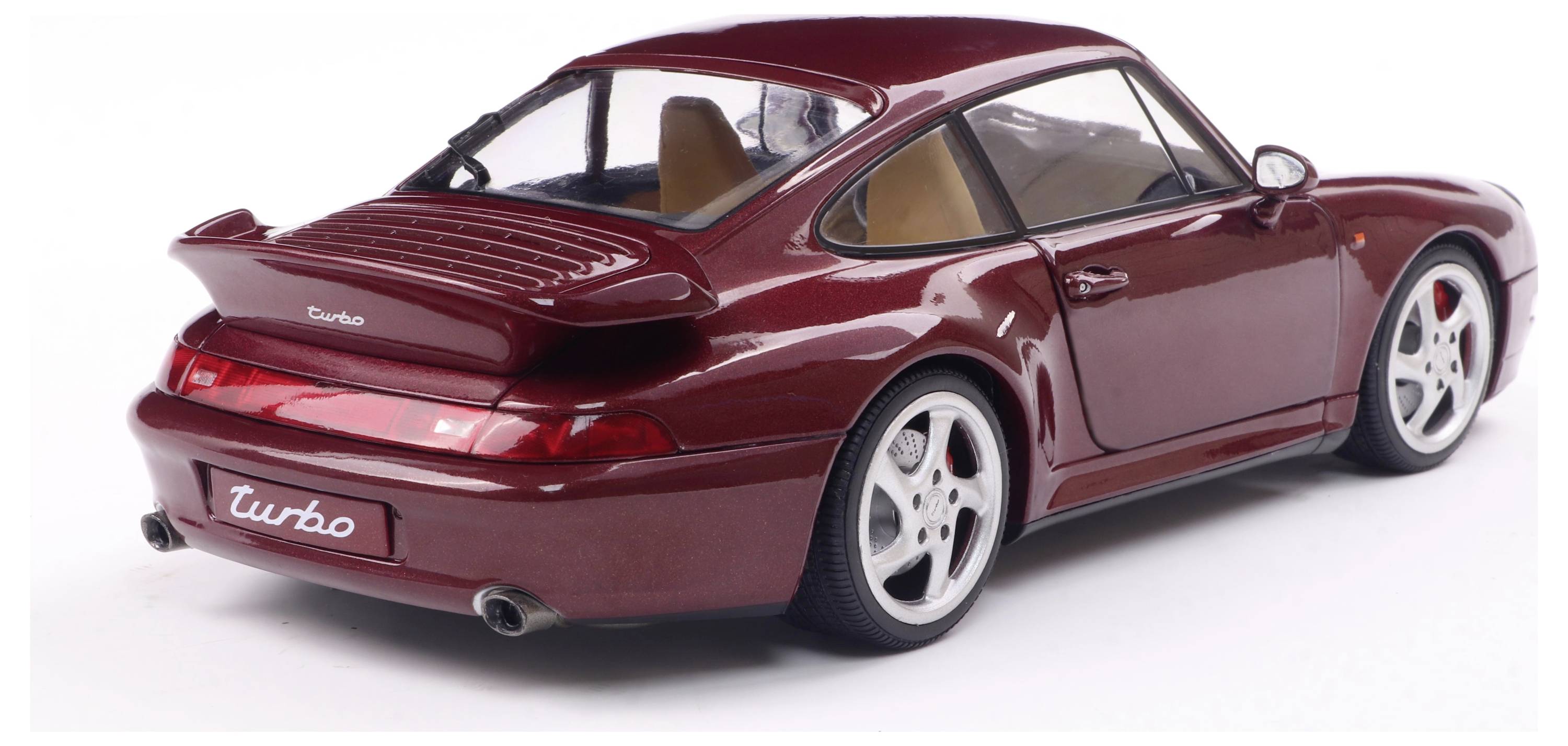 Ein rotes Modellauto eines Sportwagens mit dem Schriftzug 'Turbo' auf der Rückseite. Seitenansicht zeigt elegantes Design und silberne Felgen.