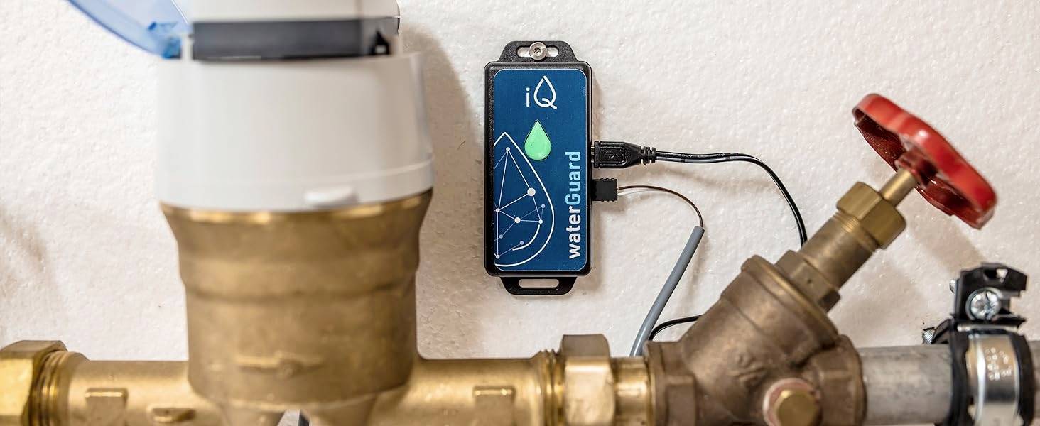 Ein Wasserleitungssystem mit einem angeschlossenen digitalen Gerät zur Überwachung. Ein rotes Ventil ist sichtbar.