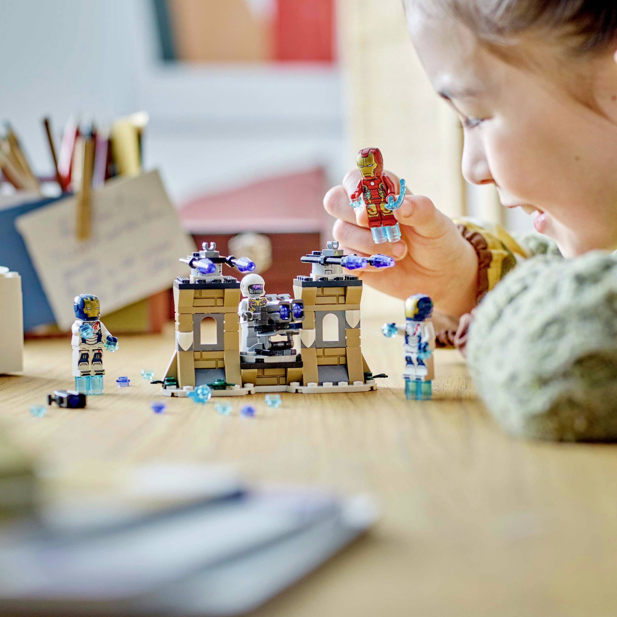 Ein Kind spielt lächelnd mit Weltraumspielzeug auf einem Tisch. Im Hintergrund sind Schreibutensilien und ein Notizblock zu sehen.