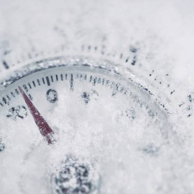 Ein frostbedecktes Thermometer zeigt etwa minus 10 Grad Celsius an. Die Temperaturen sind tief, wie die Eisschicht darauf zeigt.
