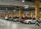 Ein weitläufiger, gut beleuchteter Parkbereich in einem Parkhaus. Verschiedene Autos parken nebeneinander zwischen orange markierten Säulen.