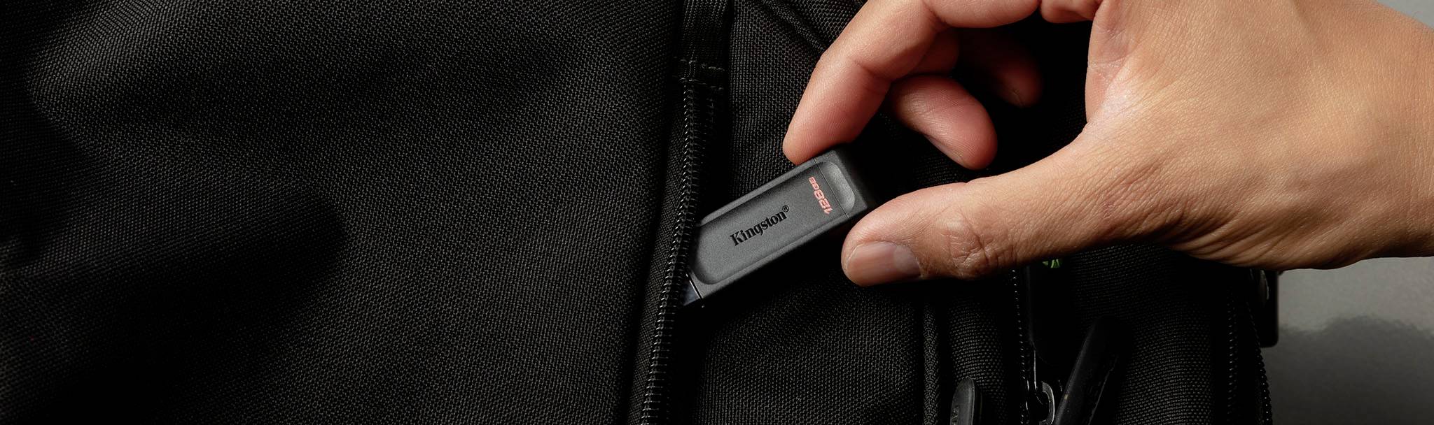 Eine Hand steckt einen USB-Stick in eine schwarze Tasche.