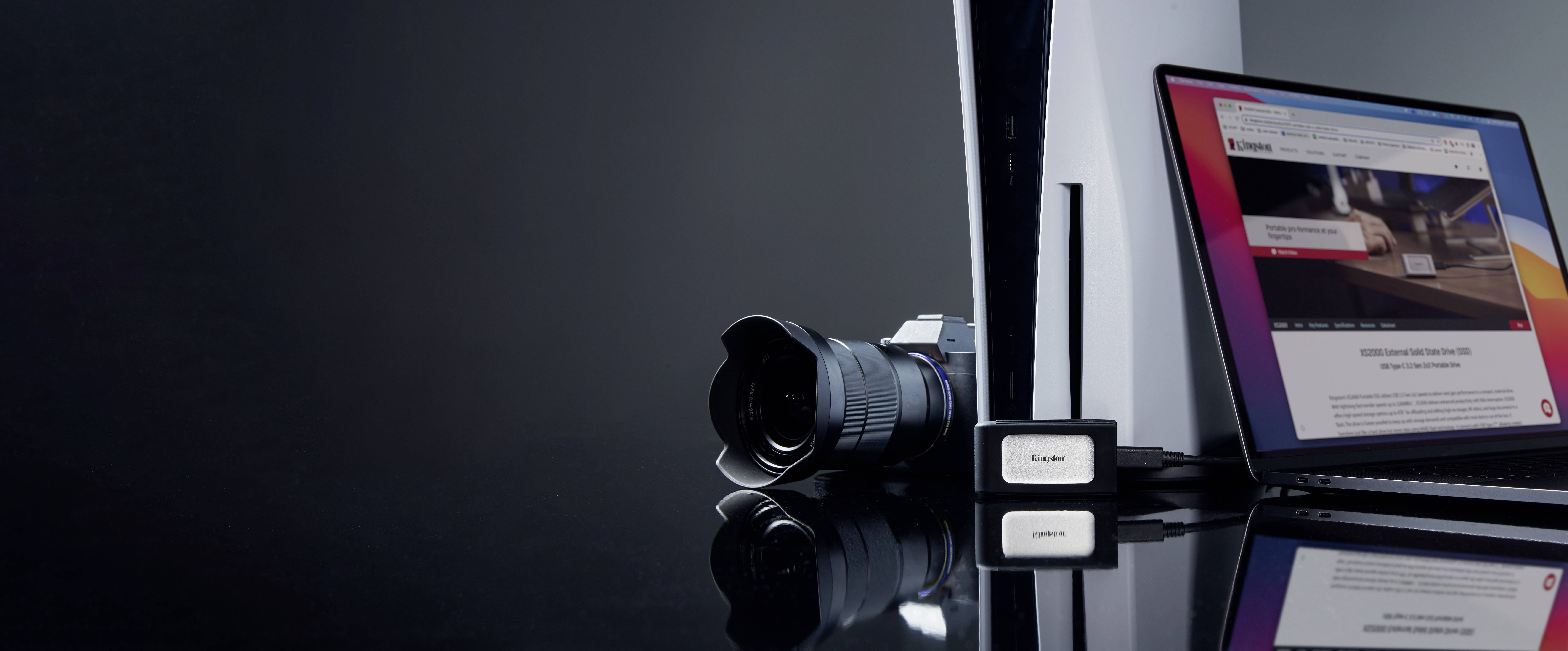 Eine PlayStation 5, eine Kamera und ein Laptop mit geöffneter Webseite stehen auf einem Tisch. Die Szene zeigt moderne Technologie.
