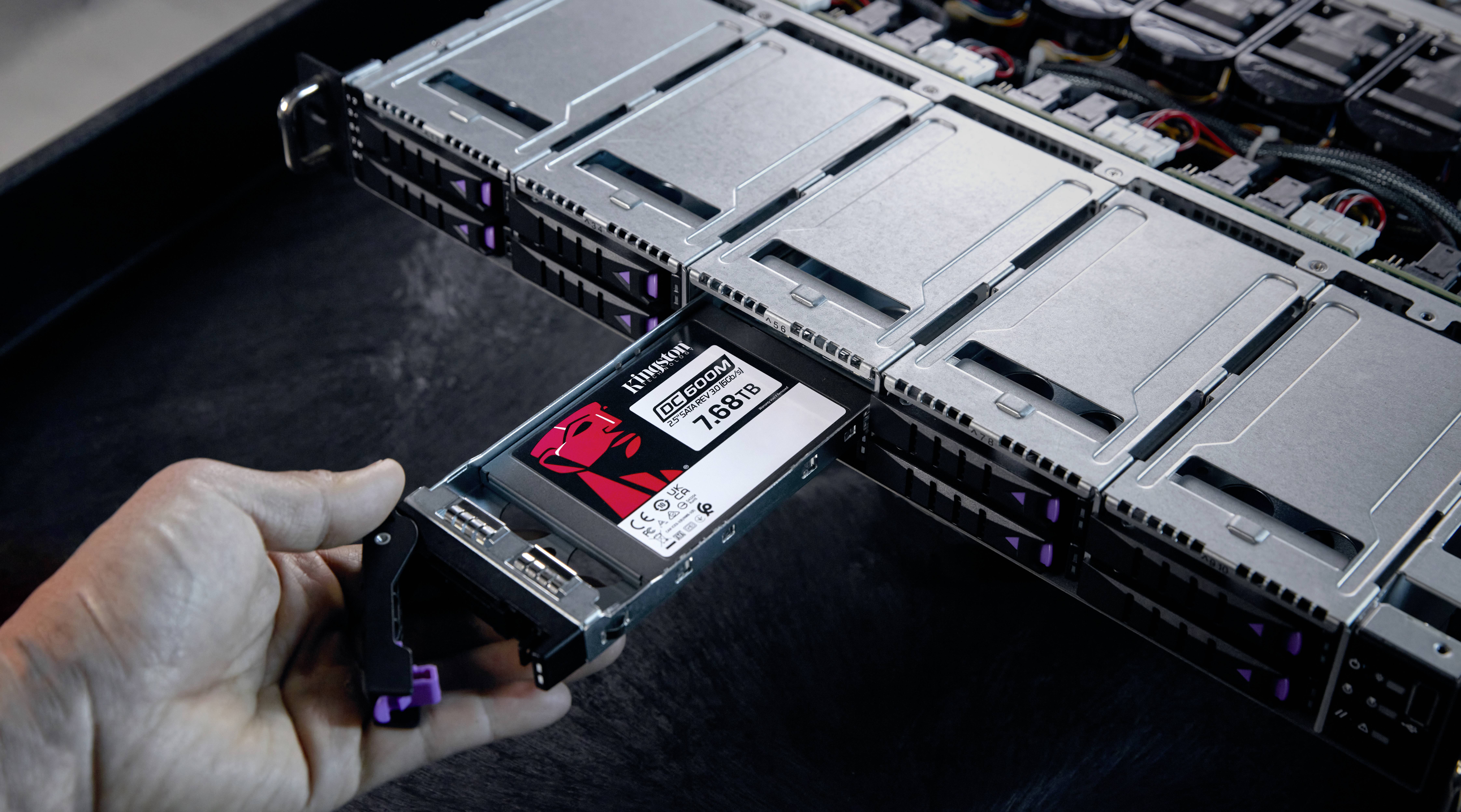 Eine Hand schiebt eine Kingston SSD mit 7,68 TB in einen Serverslot ein. Die Szene zeigt einen Server mit mehreren Festplatteneinschüben.