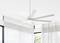 Ein weißer Deckenventilator mit mehreren Flügeln ist an der Decke eines hellen Raums mit großen Fenstern und halbtransparenten Vorhängen installiert.