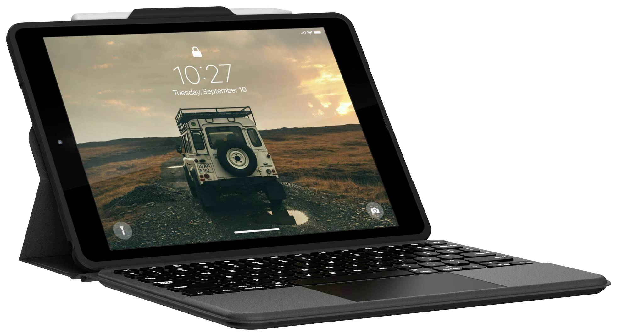 Ein Tablet in einem schwarzen Gehäuse mit Tastatur zeigt ein Bild von einem Jeep auf einem Weg in einer ländlichen Landschaft bei Sonnenuntergang.