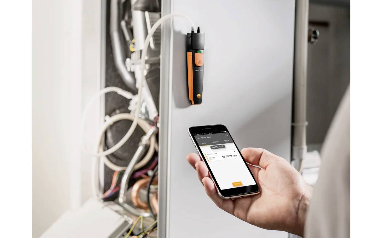 Eine Person verwendet ein Smartphone, um Daten von einem an einem Maschinenkabel befestigten Messgerät abzurufen.