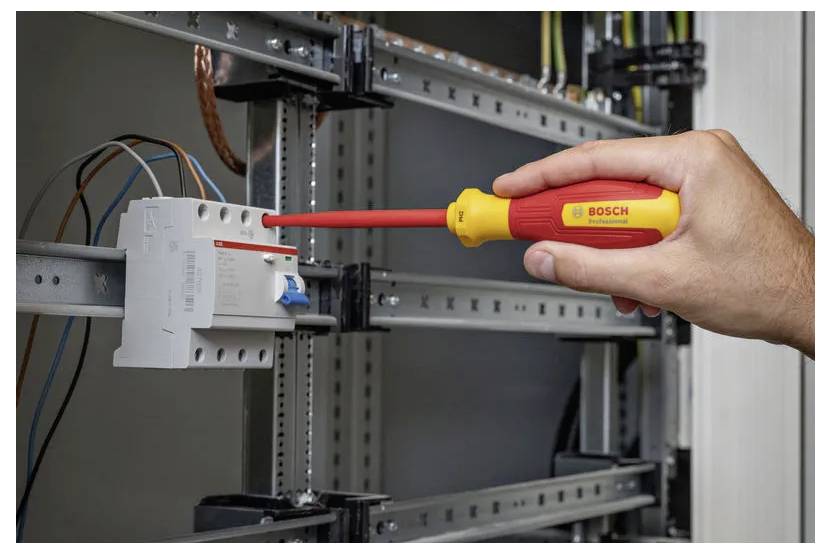 Eine Hand zieht eine Schraube an einer elektrischen Schaltanlage mit einem isolierten Schraubendreher an und gewährleistet dabei die sichere Installation von Verkabelungskomponenten.