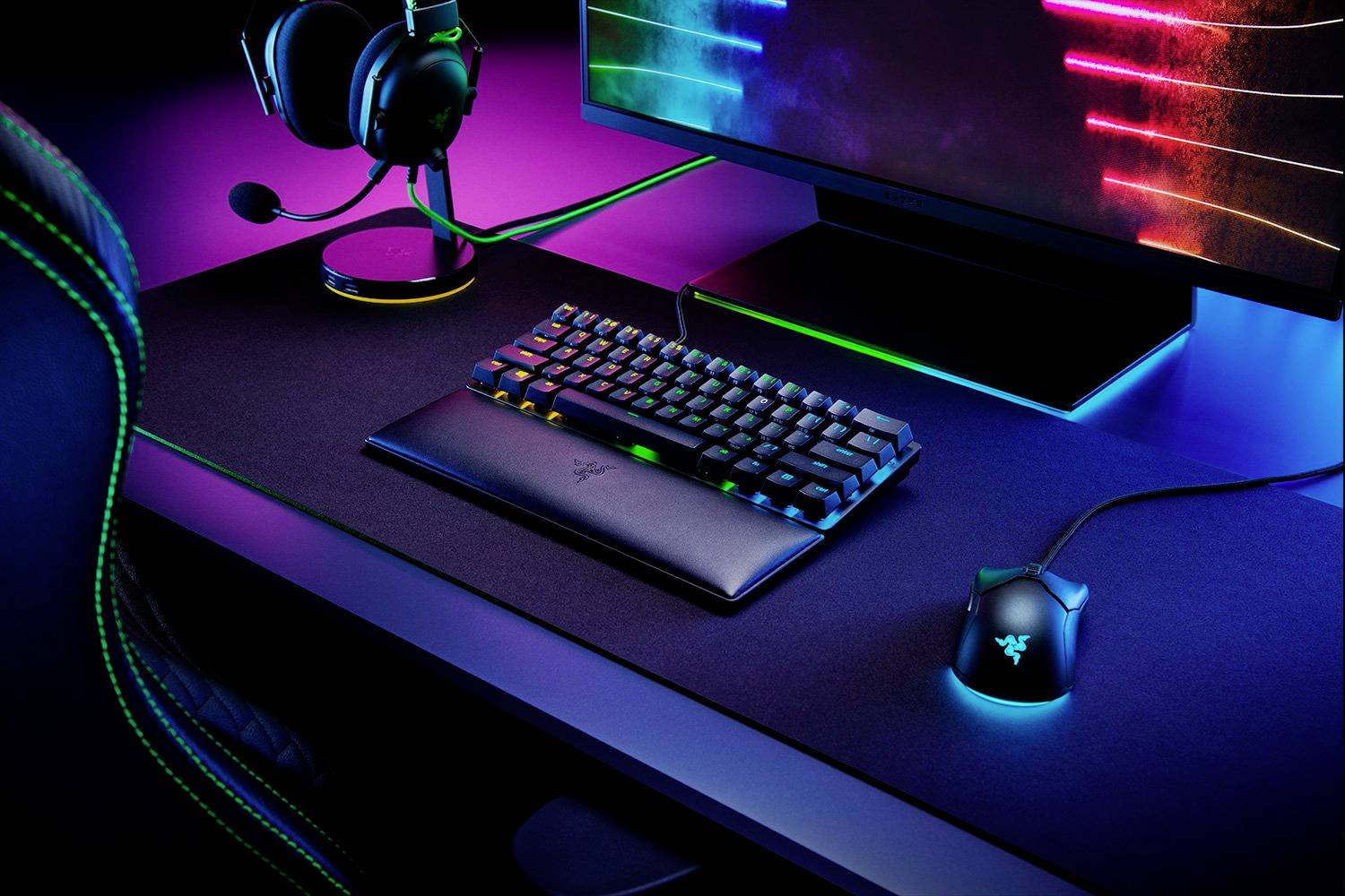 Ein Gaming-Setup mit beleuchteter Tastatur, Maus und Headset vor einem Monitor. Betont modernes Design und RGB-Beleuchtung.