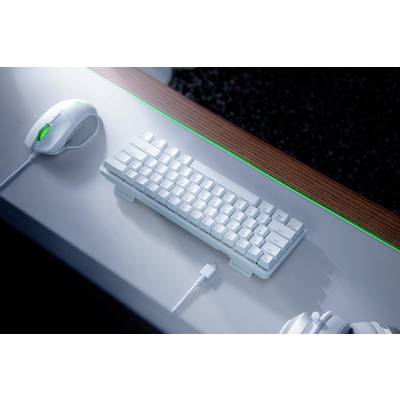 'Weißes Gaming-Keyboard mit kompaktem Design', auf einem Schreibtisch, umgeben von weißen Gaming-Accessoires.