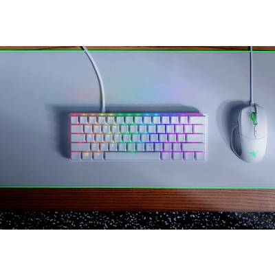 Tastatur mit Regenbogenbeleuchtung und weiße Maus auf grauem Mauspad, grün umrandet, auf Holzoberfläche.