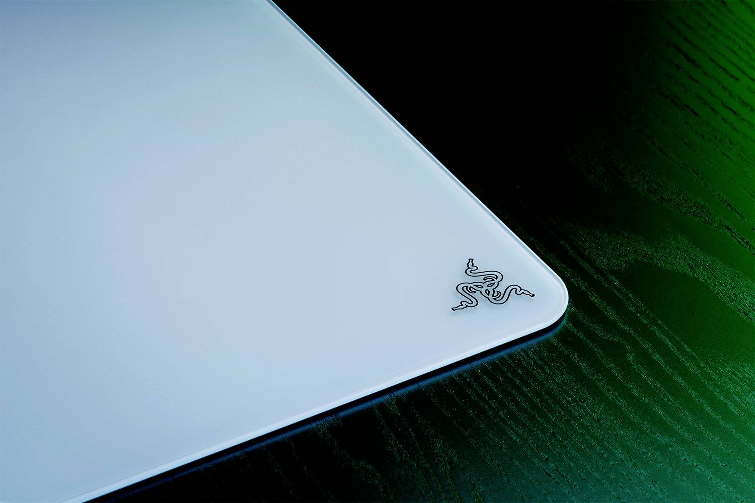 Laptopdeckel in hellem Metall mit einem stilisierten Logo in der Ecke, auf einem dunklen Holzuntergrund.