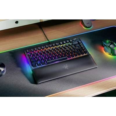 Eine beleuchtete Gaming-Tastatur mit RGB-Leuchten auf einem Schreibtisch. Daneben sind eine Gaming-Maus und ein beleuchtetes Mauspad.