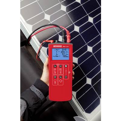 Eine Person hält ein rotes digitales Messgerät neben einem Solarpanel. Das Gerät zeigt Messwerte zur Solarenergieeffizienz an.