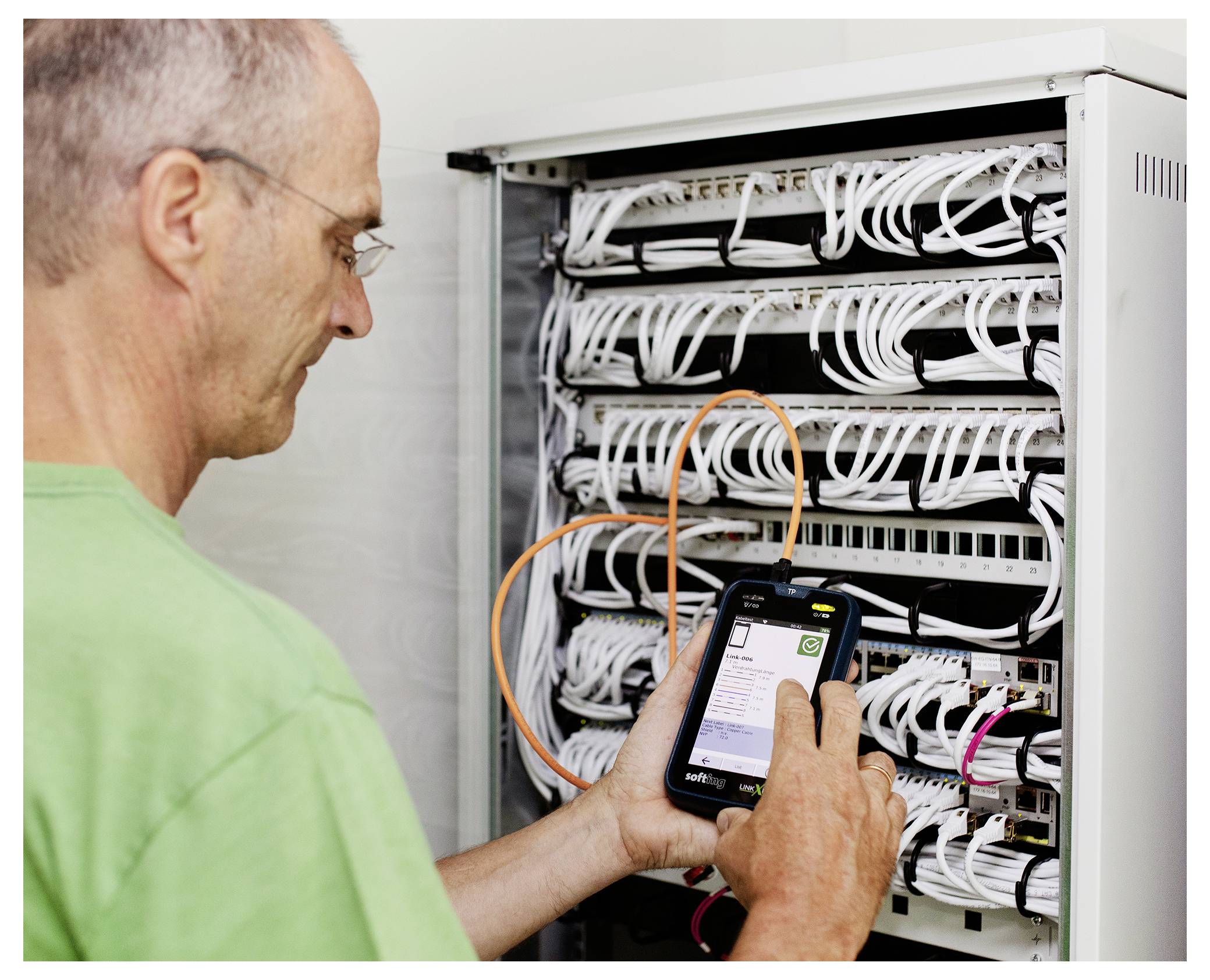 Techniker verwendet ein Smartphone zur Inspektion und Fehlerbehebung von Netzwerkkabeln in einem Servergestell.