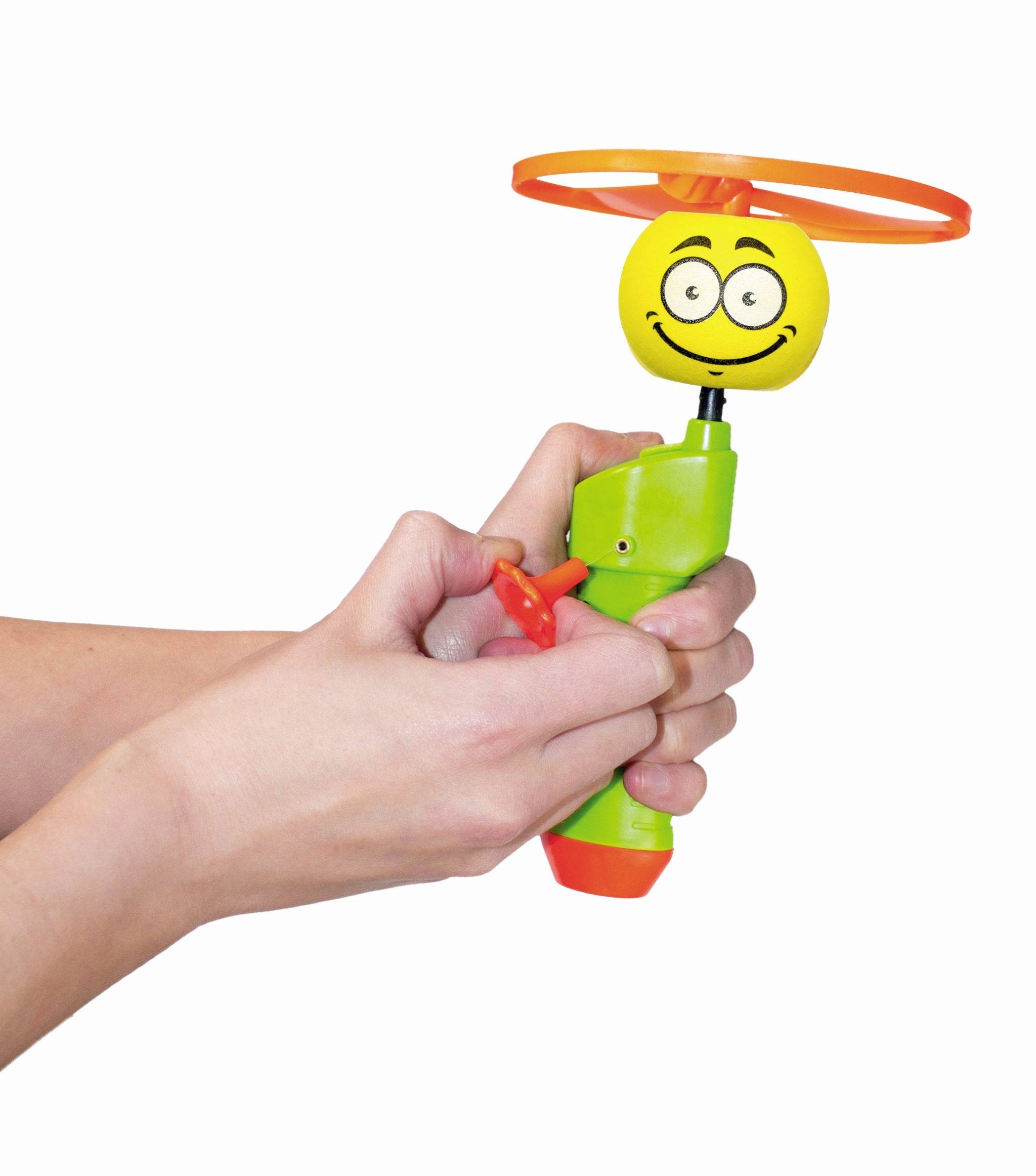 Eine Hand hält ein grünes und oranges Spielzeug mit einem lachenden Gesicht und einem Propeller oben, bereit zum Starten.