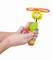 Eine Hand hält ein grünes und oranges Spielzeug mit einem lachenden Gesicht und einem Propeller oben, bereit zum Starten.