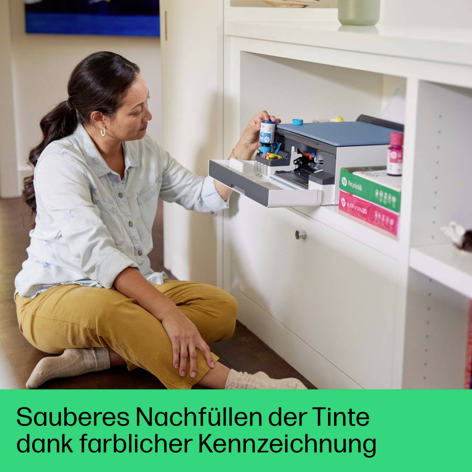 Eine Frau füllt Tinte in einen Drucker nach. Die Tintenflaschen sind farblich gekennzeichnet zur leichteren Identifizierung.