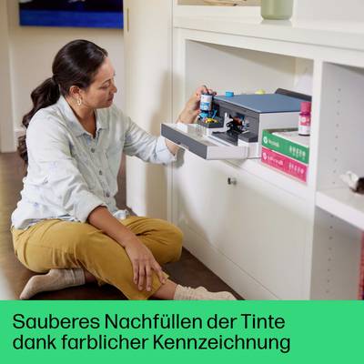 Eine Frau füllt Tinte in einen Drucker nach. Die Tintenflaschen sind farblich gekennzeichnet zur leichteren Identifizierung.