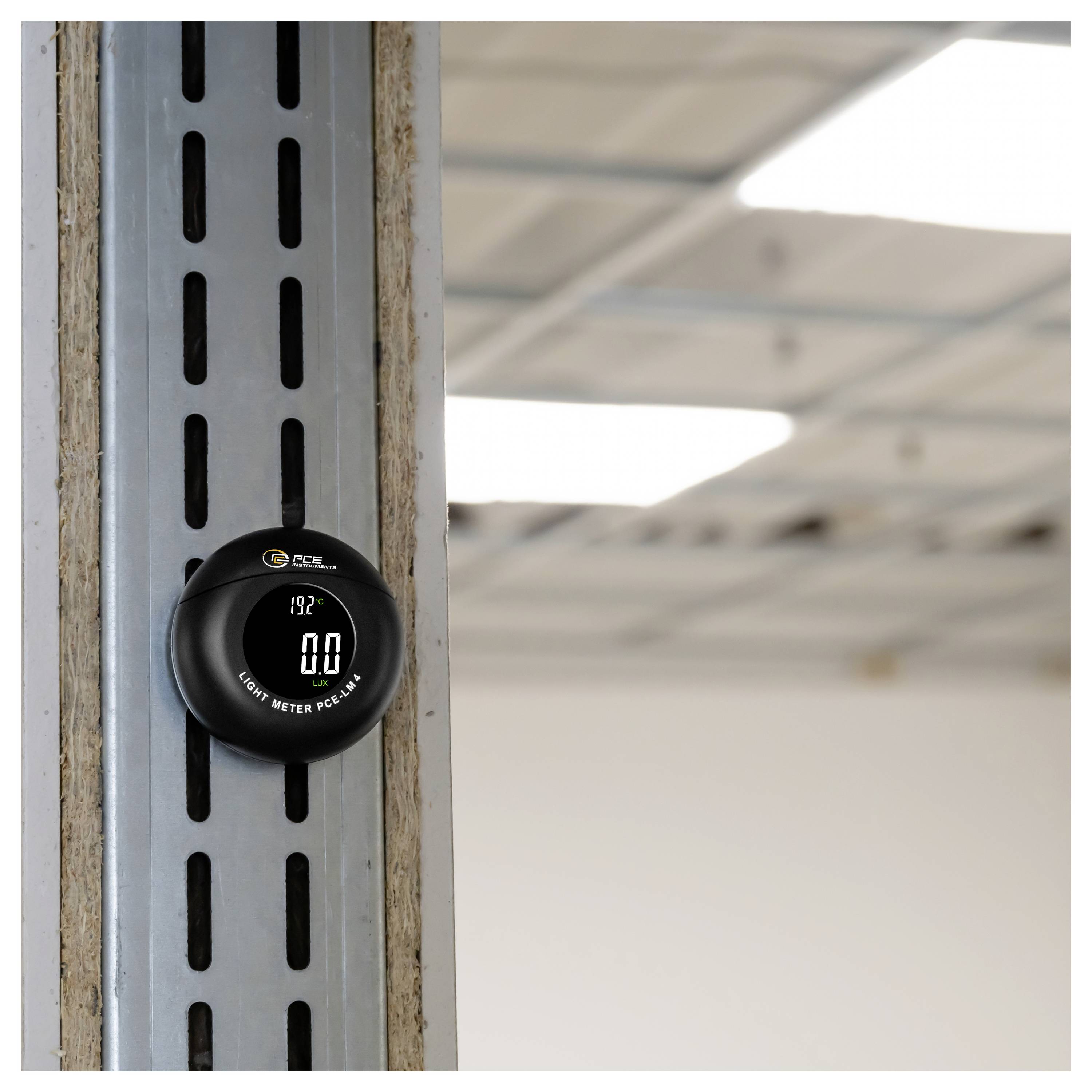 Nahaufnahme eines digitalen Luxmeters, das auf einem Metallregalbrett montiert ist und einen Wert von 0,0 in einem Innenraum anzeigt.